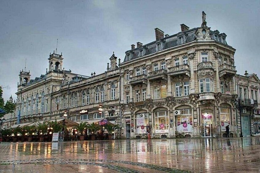 A historic building with ornate architecture, a reflective courtyard, and a statue. 1