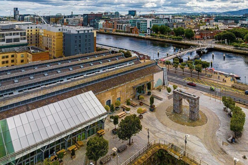A riverside urban area with a large industrial building, a roundabout, and a bridge in the background. 2
