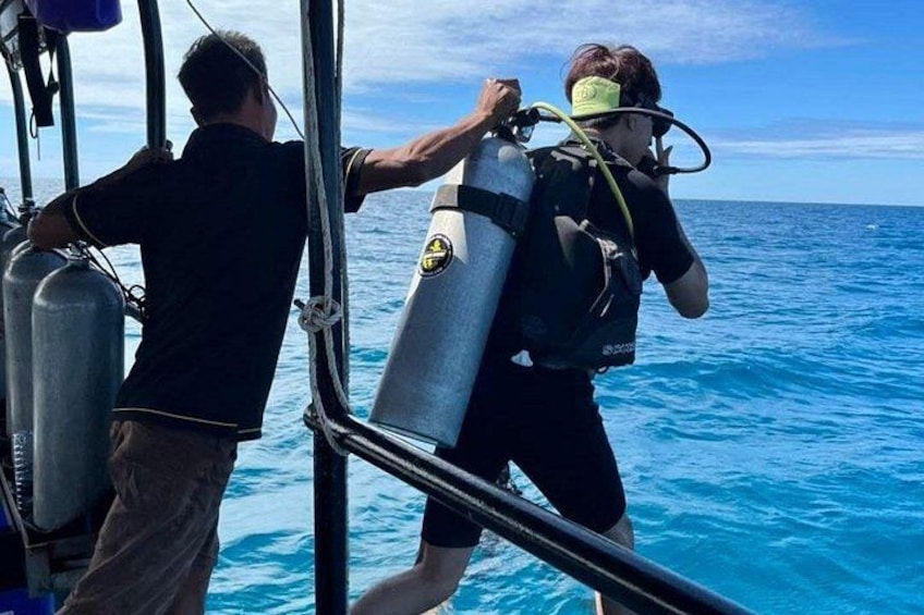 Two people on a boat preparing scuba diving equipment. 3