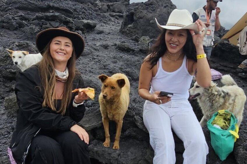 Two people sitting on rocks with dogs, one wearing a cowboy hat. 2