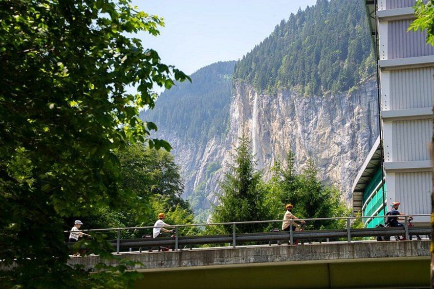 A bridge with people walking, a mountain, and trees. 2