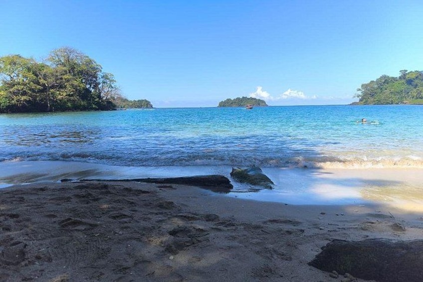A beach with clear water, a boat, and distant islands. 2