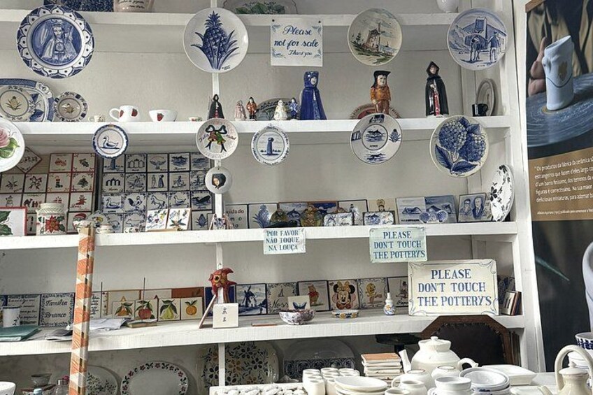 A pottery shop with shelves of ceramic items and signs instructing not to touch the pottery. 4