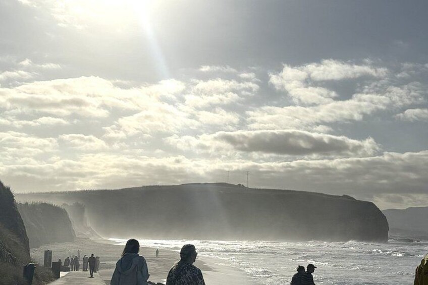 A coastal landscape with cliffs, a beach, and people walking along the shore. 2