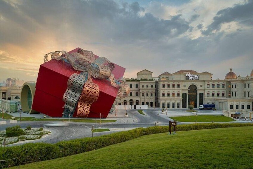Une grande sculpture rouge se dresse devant un bâtiment classique, doté de coupoles et de colonnes. 3