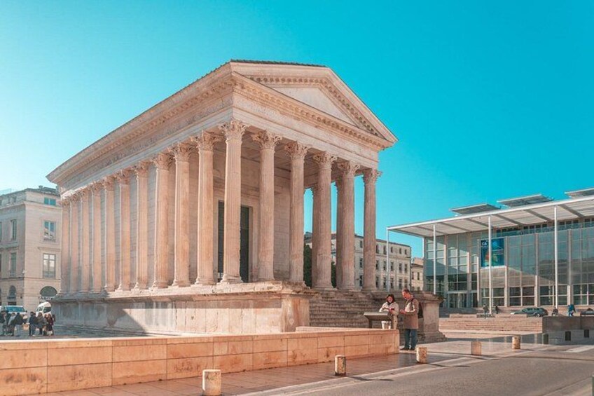 A neoclassical building with columns, a fountain, and a modern glass structure in the background. 1