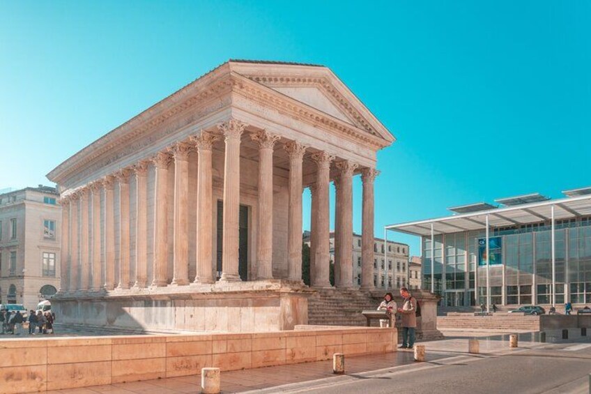 A neoclassical building with columns, a fountain, and a modern glass structure nearby. 1