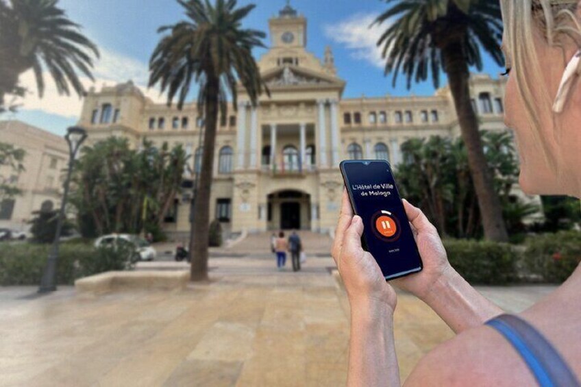 A person holding a smartphone with a map application, palm trees, and a large building in the background. 5