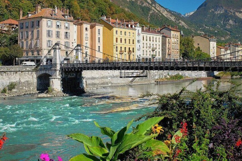 A river with a bridge, buildings, and mountains in the background. 2