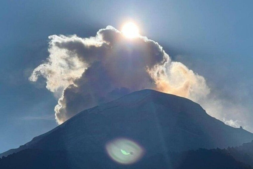 A mountain with a sun shining through clouds. 4