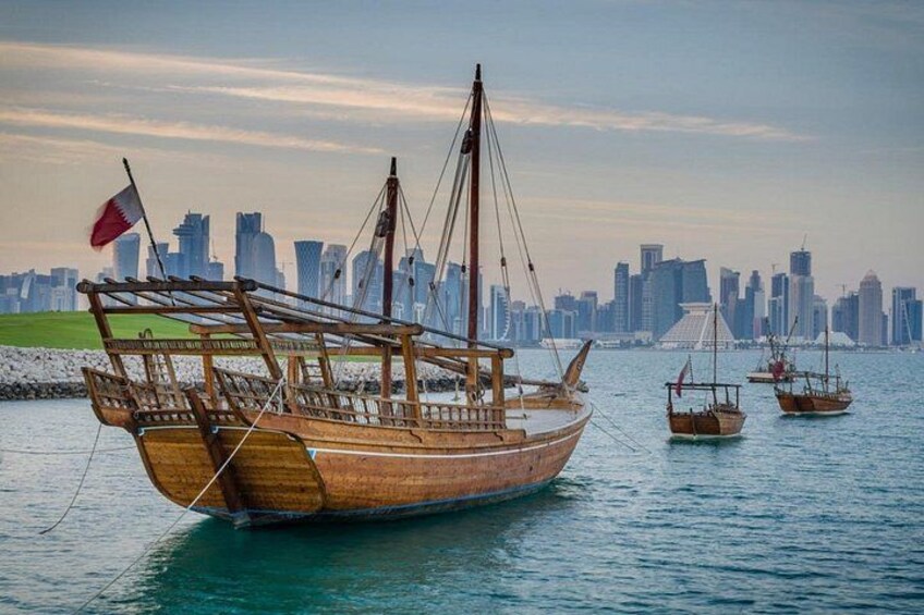 Un'imbarcazione di legno con una bandiera, uno skyline cittadino sullo sfondo e un'altra barca nelle vicinanze. 4