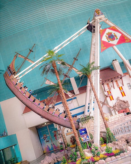 A pirate ship ride in an indoor amusement park with palm trees and colorful decorations. 3