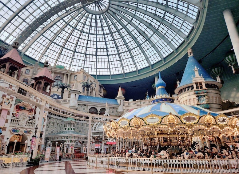 A large indoor amusement park with a glass-domed ceiling, a carousel, and various themed buildings. 4
