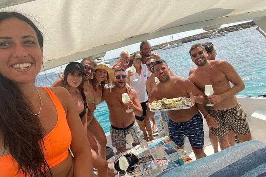 Un groupe de personnes se trouve sur un bateau, autour d’une table où sont disposés de la nourriture et des boissons. 5
