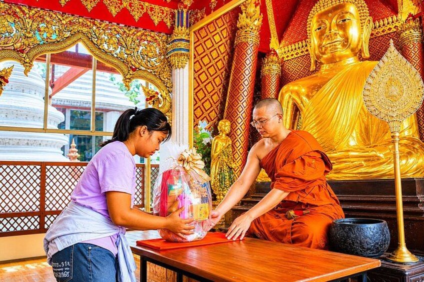 Un moine vêtu d’une robe orange effectue un rituel en compagnie d’une femme portant un chemisier violet. 1