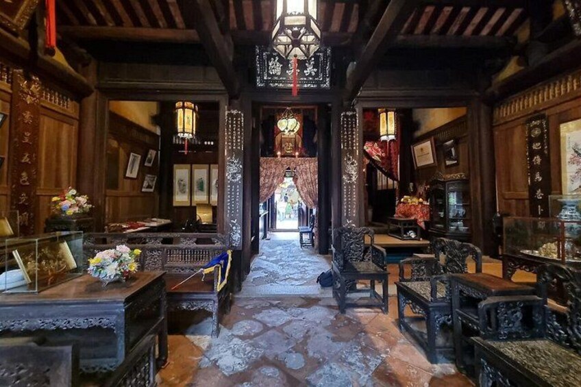 A traditional wooden interior with ornate furniture, a stone floor, and hanging lanterns. 5