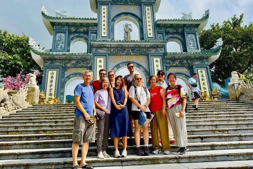 A group of people standing on steps in front of a traditional Chinese gate with inscriptions. 4