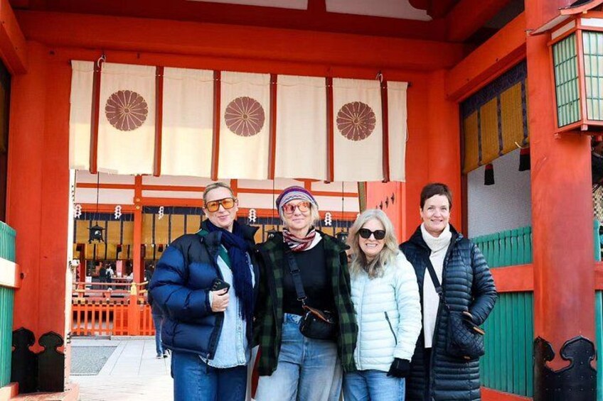 En gruppe mennesker står foran en traditionel japansk torii-port. 1