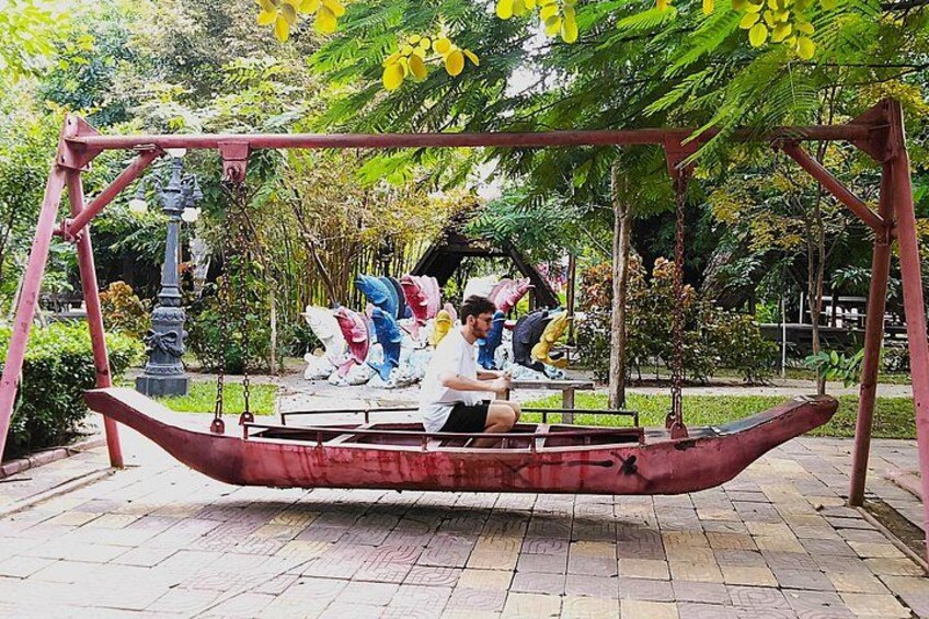 Una persona sentada en un columpio con forma de barco en un parque. 2