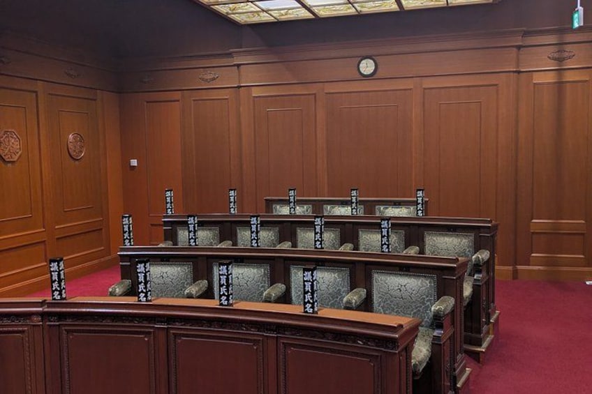 A courtroom with wooden paneling and a red carpet. 4