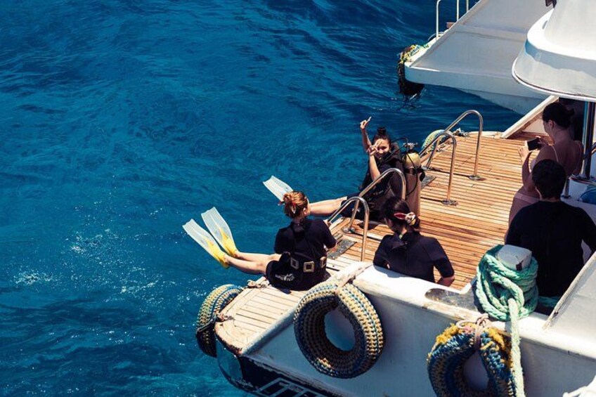 A group of people on a boat with diving equipment, preparing for a dive. 5