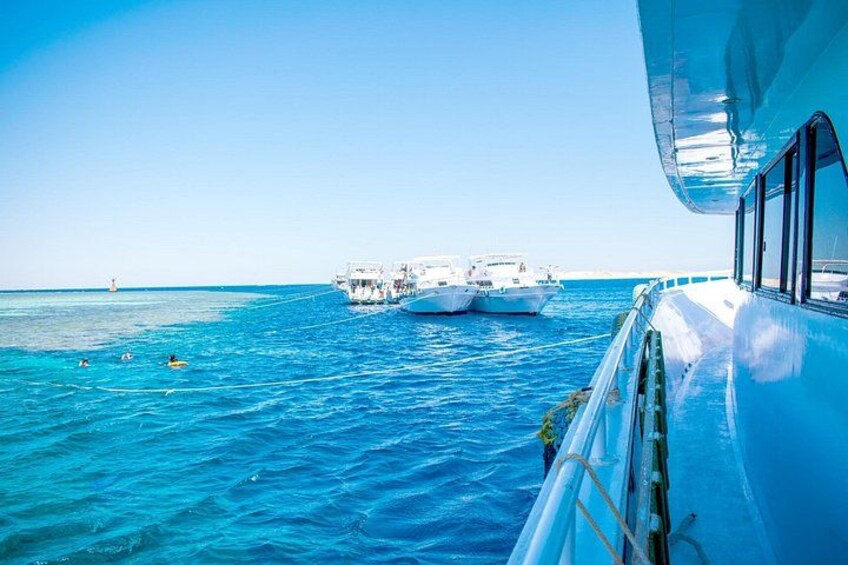A clear blue sea, a boat, and a distant lighthouse. 3