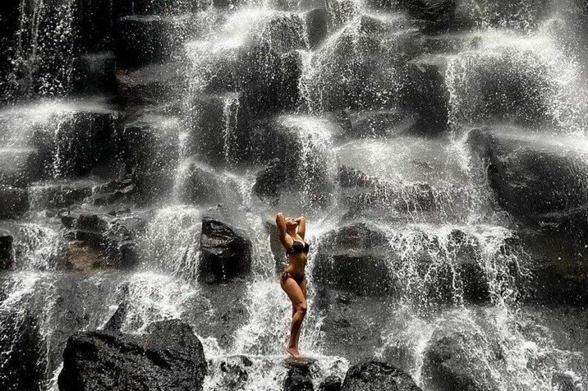 A person standing on rocks with water cascading over them. 1