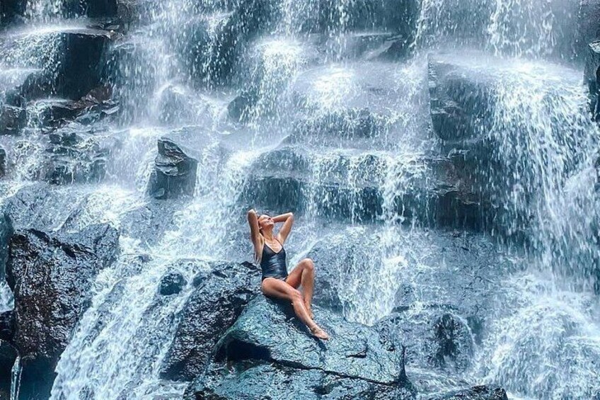 A person sitting on rocks by a waterfall. 2