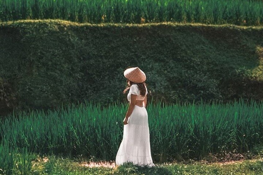 A woman in a white dress and straw hat standing in a field of tall grass. 4