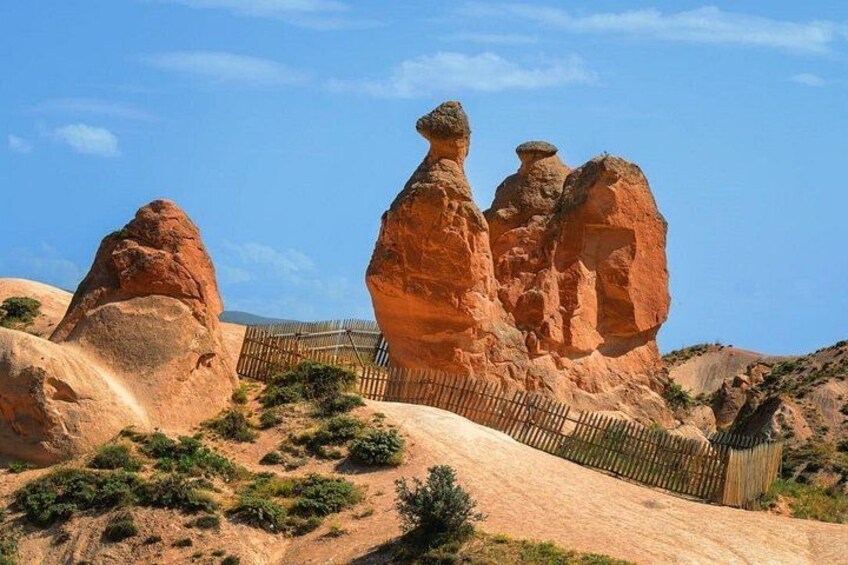 A desert landscape with prominent rock formations and a wooden fence. 2