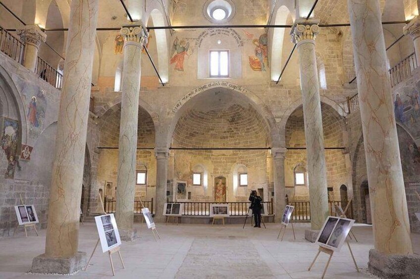 Un interior con techos altos, columnas abovedadas y frescos. 5