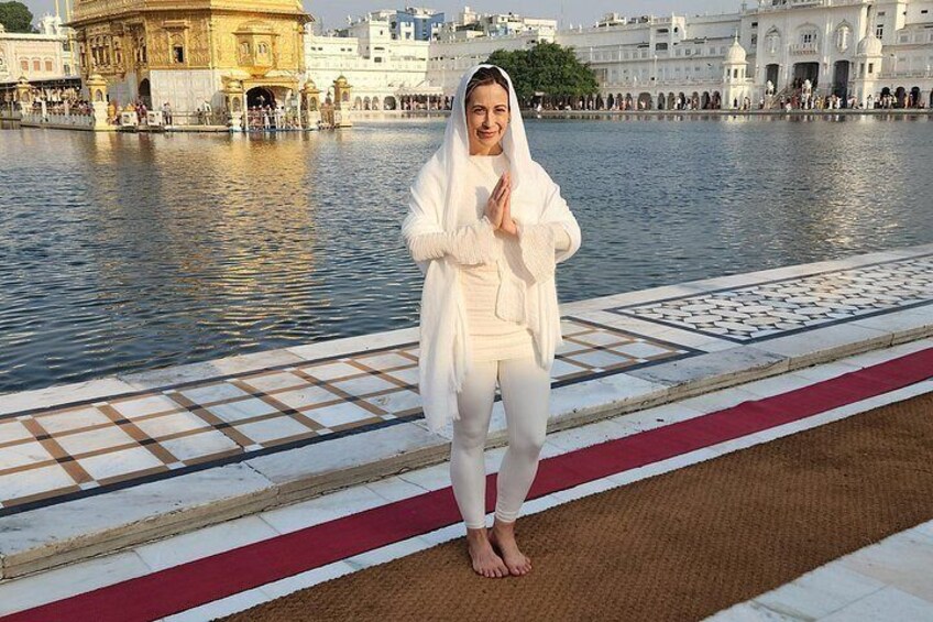 A person standing by a water body with a temple in the background. 1