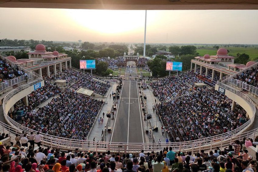A large stadium filled with spectators, a road in the center, and a clear sky. 4