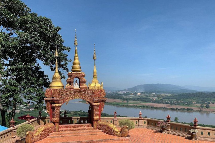 Un templo con agujas doradas, un río y un paisaje montañoso al fondo. 3