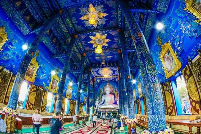 Interior de un templo con intrincadas decoraciones en azul y dorado, una estatua central y un gran diseño en el techo. 2