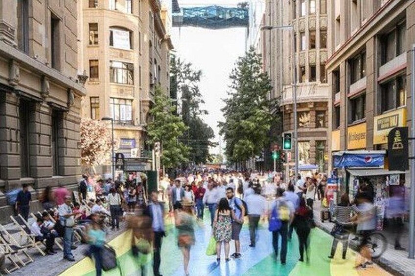Eine belebte Stadtstraße mit Fußgängern, Gebäuden und Bäumen. 1