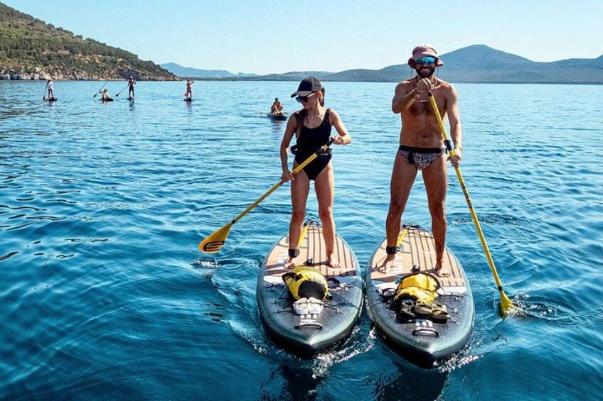 Due persone che fanno paddleboard su un lago tranquillo, con montagne sullo sfondo. 1
