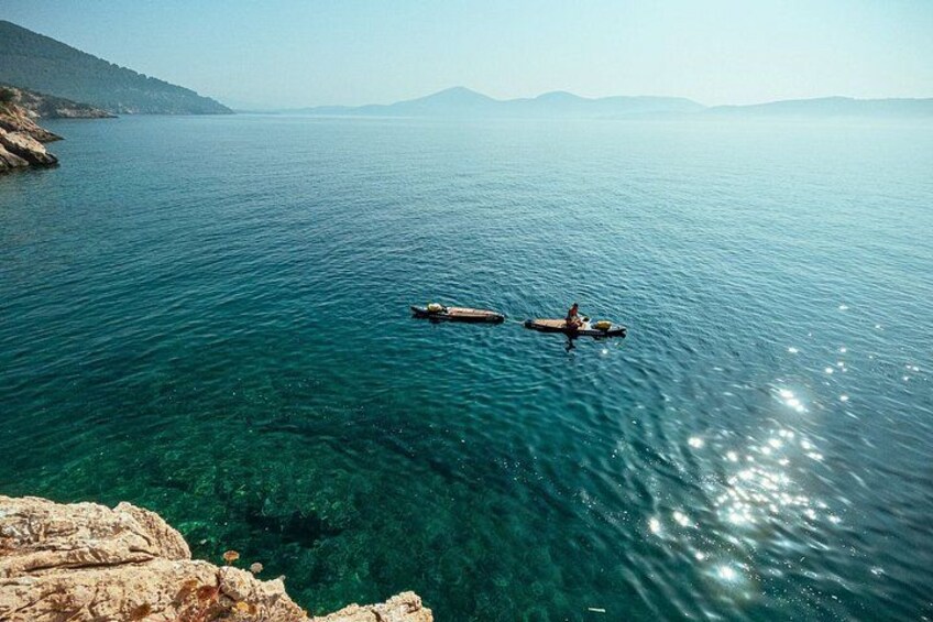 Mare calmo con due imbarcazioni, acqua limpida e costa rocciosa. 5