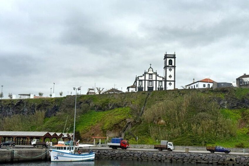 A coastal town with a prominent church, a dock with a boat, and a hillside with buildings. 5