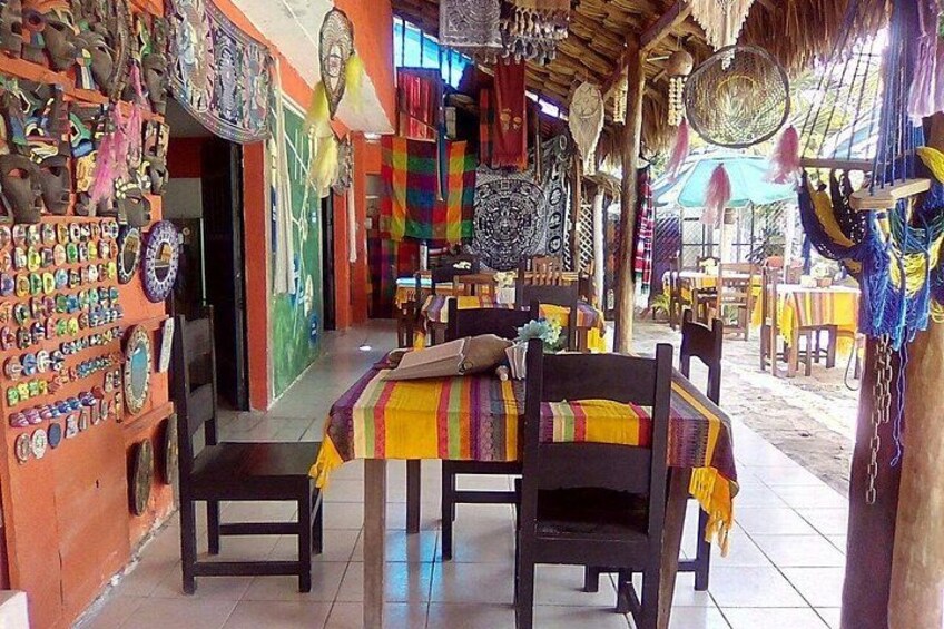 Un interior colorido con una mesa dispuesta para comer, rodeada de diversos objetos decorativos y textiles. 2
