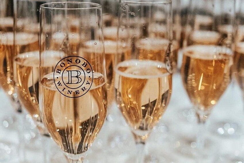 Mehrere Gläser eines goldfarbenen Getränks, vermutlich Champagner, mit einem Logo am Glas. 3