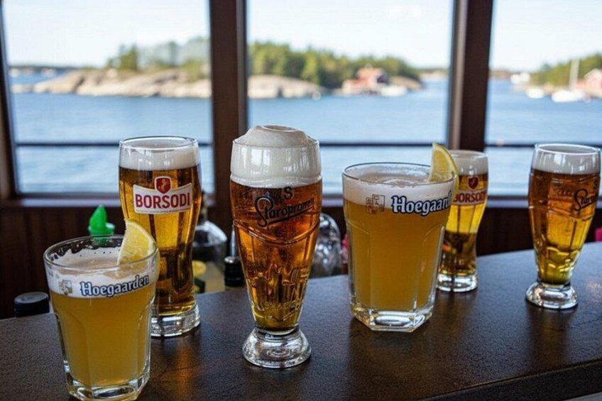 A bar with several glasses of beer, some with ice, and a view of a body of water through a window. 5