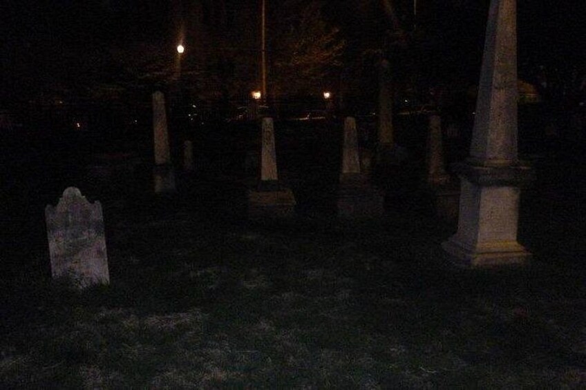 Un cementerio nocturno con lápidas y una farola. 1