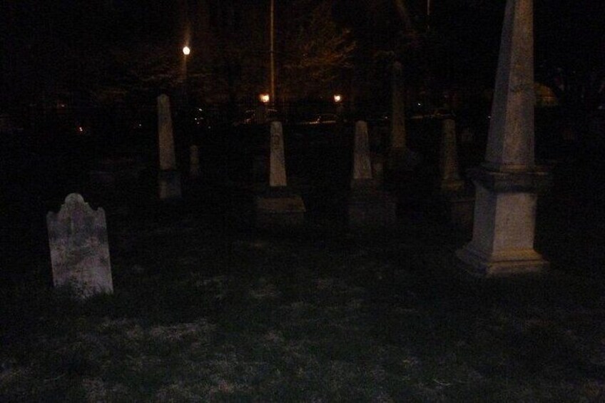 Een begraafplaats in de nacht met grafstenen en enkele lantaarns. 3