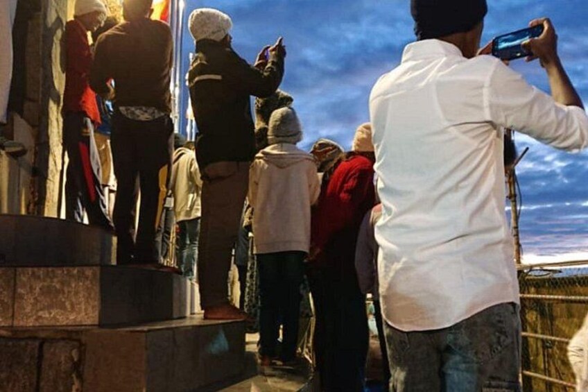 A group of people standing on a platform, some taking photos. 5