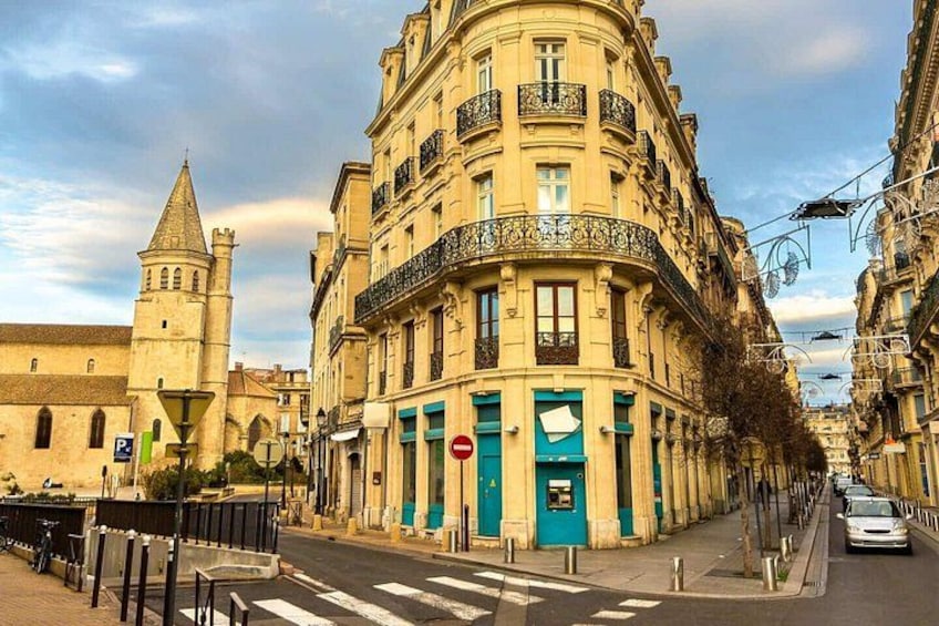 A historic building with a tower, a street with cars, and a clear sky. 4