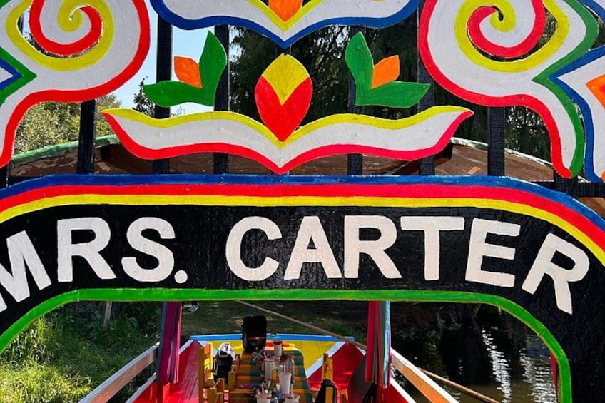 A colorful boat with 'MRS. CARTER' written on it, passengers, and a river. 2