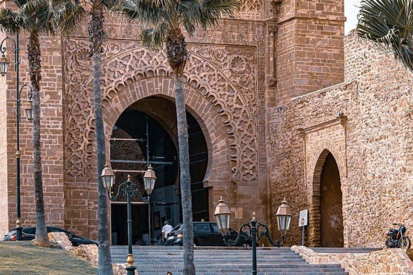 A historic building with intricate arches and columns, palm trees, and a bicycle parked nearby. 1