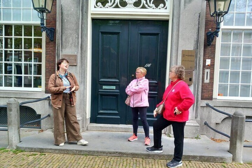 Three people standing on a sidewalk in front of a building with a black door. 3