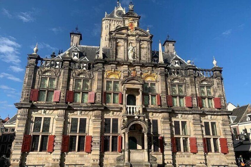 A historic building with ornate architecture, red shutters, and a clock tower. 2